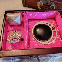 Top angle showing all three jewelry items in pink fabric-lined wooden box: large silver pyramid ring, openwork leaf ring, and circular brooch with black onyx and garnet.