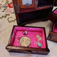 All four items displayed inside a small wooden box with pink satin lining