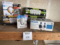 Boxed GE Soft White LED classic shape bulbs 4-pack, Philips halogen reflector bulb, Feit Electric LED dimmable bulb packs, and Philips phone system boxed.
