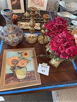 Top-down view of lot showing sunflower print, rose topiaries, candle holders, vase, and plate stand all on a table.