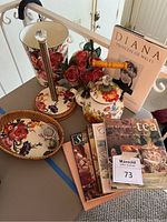 Photo of floral kitchen set items including paper towel holder, teapot, serving trays, trash can, assorted tea books, and Diana Princess of Wales book.