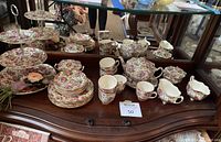 Group shot of all china set pieces on wooden surface in front of mirror