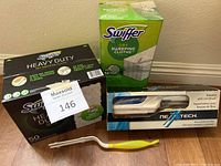 Photo showing boxed Swiffer dry sweeping cloths (50 and 86 count) and Neatech steamer with lint brush in packaging, along with a lint brush with yellow-green handle.