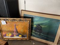 Overall view of both framed paintings leaning against wall