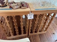 Front view of two unfinished wooden wine racks side by side shown with glassware and decorative items on top