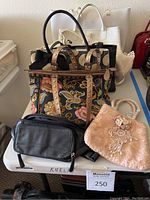 View of five assorted women's handbags placed together on a table showing variety in size and style.