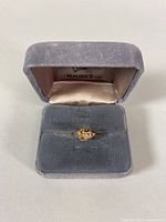 Front view of the 10K gold ring in the gray velvet Maurice Ltd. box, showing the intricate top design.