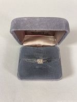 Front view of the white gold diamond ring in a grey velvet jewelry box.