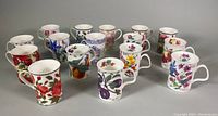 Front angled view showing 16 assorted vintage china mugs with various flower designs in vibrant colors and white handles.