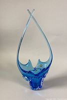 Front view of the tall blue freeform blown glass bowl with curved, crossing points and thick base.