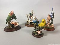 Four vintage bird sculptures by Dave Grossman shown together on white background, each mounted on wooden bases with floral or branch elements.