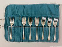 Seven forks in teal felt sleeve with pockets