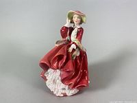 Front view of the Royal Doulton porcelain figurine showing detailed facial expression, red dress, and flowing skirt with white ruffled underskirt.