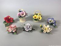 Seven vintage Andrea China floral porcelain figurines displayed in a group. Includes various colors and flower types in single flower forms and woven basket forms.