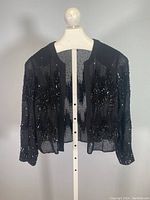 Front view of black J Mendel shrug jacket with embroidered black sequins in good condition.