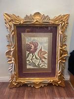 Front view of large, ornate gold frame with floral print inside showing overall size and condition.