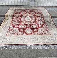 Full view of rug laid on asphalt against a white brick wall