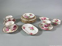 Full set showing sugar bowl, stacked plates, three teacups with matching saucers and small serving dish on a gray background