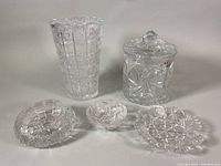 Five vintage pinwheel cut crystal pieces: a tall vase, cookie jar lid, candy dish, ashtray, and small bowl arranged on white background.