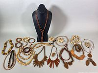 Overview of the entire vintage wood jewelry collection, showing various necklaces, bracelets, and earrings arranged on a table and bust. Includes different styles of wooden beads and pendants.