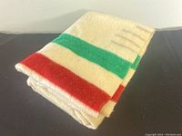 Folded blanket showing cream base with red and green stripes