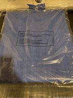 Photo of a folded blue tarp sealed in clear plastic packaging showing some product text and a metal grommet near the edge.
