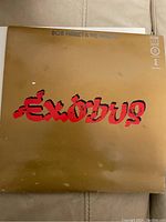 Top view of the vinyl album cover showing 'Exodus' title in large red lettering with brown background. Visible wear and damage on cover.