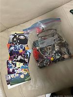 Photo showing a ziplock bag filled with various pieces of costume jewelry and a fan of colorful Beatles postcards.