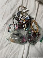 Photo showing assorted costume jewelry including bracelets and necklaces, some in plastic bags.