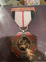 Front view of ELO Greatest Hits medal with ribbon showing detailed enamel design and inscription.