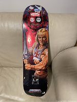 He-Man collectible skateboard deck with character artwork and brand logos, showing used condition.