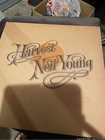 Photo shows front cover of Harvest vinyl record by Neil Young with beige background and vintage lettering.