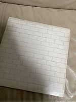 Top side of the album cover with white brick wall design showing wear and slight discoloration.