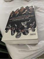 Photo of thick paperback book titled The Walking Dead Compendium One showing front cover artwork featuring main characters and zombies, indicating it contains 42 issues of the comic book series.