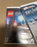 Photo shows two sealed Nintendo Wii game cases: LEGO Harry Potter and Ski Slam. LEGO Harry Potter cover depicts LEGO style Harry Potter characters in front of Hogwarts. Ski Slam cover shows snowy mountain landscape.
