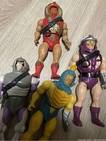 Four vintage Infaceables action figures on wood floor, showing damaged faces and details of costume.