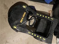 Black molded plastic vintage Knight Rider themed pedal car with yellow decals and single seat.