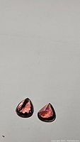 Pair of pear cut purple-pink tourmaline gemstones laid on a flat surface
