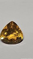Detailed front view of a pear-shaped golden citrine gemstone with faceted cut and rich color.