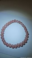 Front view of the strawberry quartz bracelet showing the round polished pink beads on elastic cord.