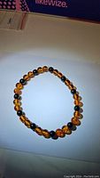 Circular stretchy bracelet with round amber and black onyx beads alternating evenly, laid on white background