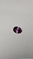 Oval cut pink-purple Ceylon sapphire on white background with visible reflections