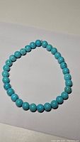 Natural turquoise blue bead stretchy bracelet laid flat on white background showing bead details.