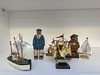 Full view of lot showing three sailor figurines and three boats of various materials and sizes