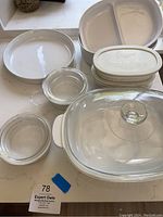 Several Corningware pieces on a table including glass casseroles, ceramic divided dish and baking dish