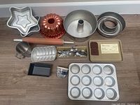 Full lot of baking pans and utensils including star-shaped pans, bundt pan, rolling pin, muffin pan, loaf pans, baking trays and spoons