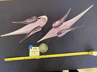 Overview of two lilac glass bird sculptures and clear glass spiral piece with measuring tape