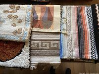Seven southwestern style textile items including throws, rugs, and latch hook hangings with geometric and southwestern motifs in earth tones.