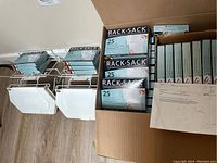 Two white metal rack sack units with sack liners hanging on wall.