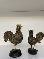 Two bird metal sculptures side by side, showing full front and side profile.